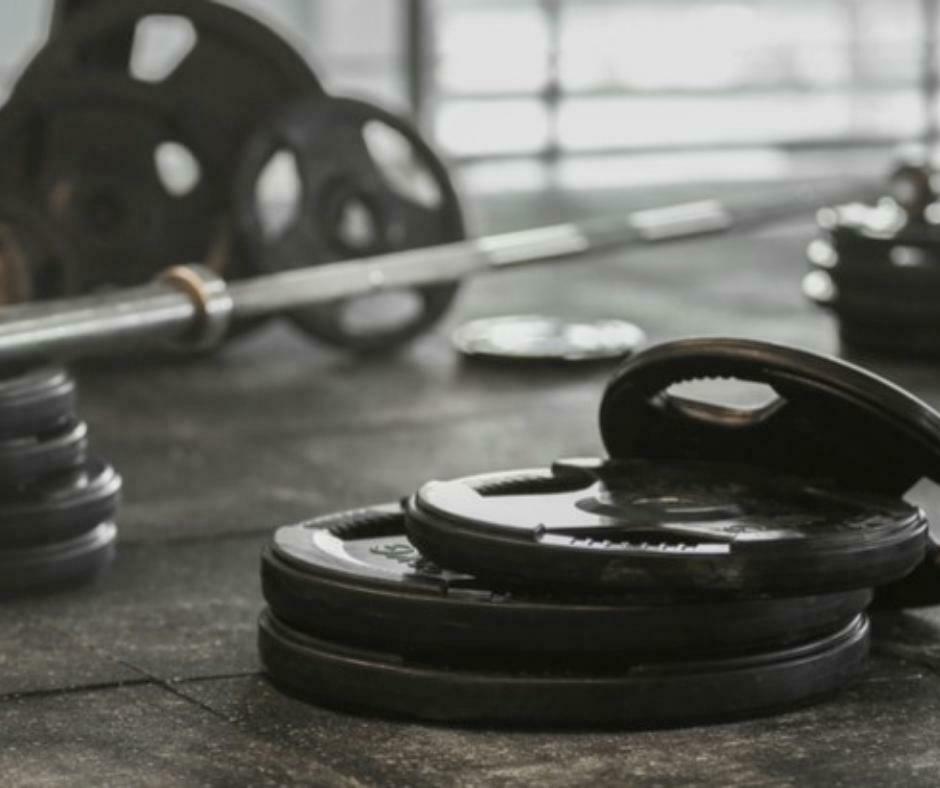 Olympic weight plates in various colors, arranged by weight, highlighting the organization of a fitness facility.